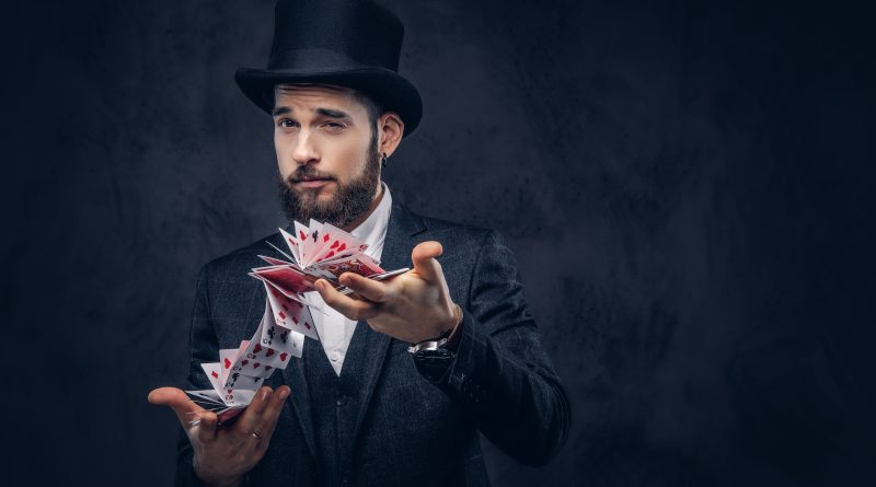 Klasyczny iluzjonista w cylindrze i garniturze prezentujący profesjonalny pokaz kart - dowiedz się, co wpływa na cenę występu w Warszawie.