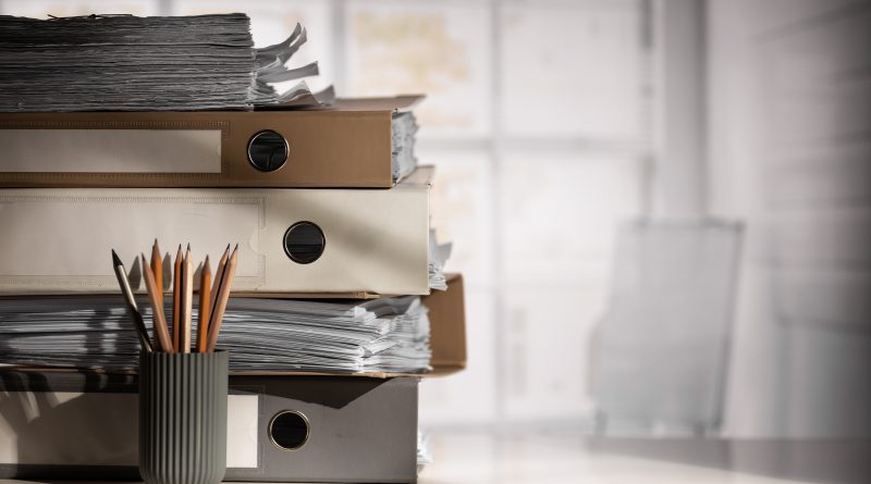 Dokumentacja papierowa i segregatory biurowe przygotowane do archiwizacji.