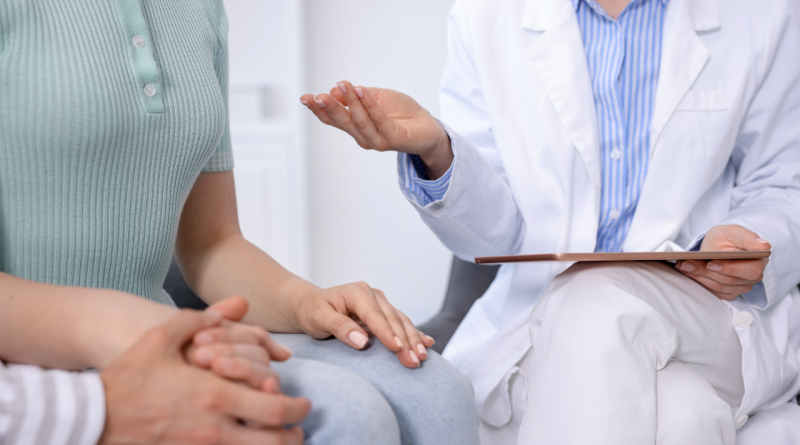 Lekarz w białym fartuchu trzymający tablet i rozmawiający z pacjentem podczas konsultacji kwalifikacyjnej do badania klinicznego.