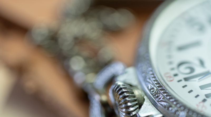 Zbliżenie makro na tradycyjny zegarek mechaniczny z misternie zdobioną kopertą i koronką.